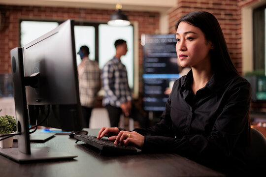 Asian software developer working with html script on terminal window, sitting at desk analyzing javascript code. Freelance coder writing innovating ai algorithm working in it programming office