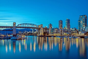 Naklejka premium Vancouver Canada, Burrard Bridge and downtown Vancouver at night, reflection of the city's night lights in the mirror water of the bay, shot done from Granville Island