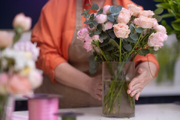 florist in the flower shop accepts orders and creates perfect pink rose arrangements, ready for delivery.