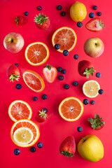 Levitating fruits and berries on a red background. View from above.