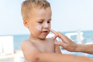 Mother applying sunscreen protection creme on cute little baby boy kid hand. Mum using sunblocking...
