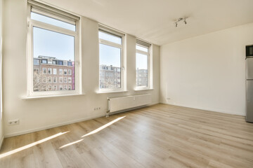 an empty room with wood flooring and large windows in the room is white walls, there are several windows