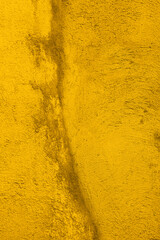 Texture of  old concrete wall painted into deep Vibrant warm golden yellow color. Decorative plaster. Abstract design grunge background. Crack on the wall surface. Vintage, retro, ancient house