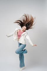 Portrait of attractive latin teenage girl in casual clothes jumping, isolated on gray background