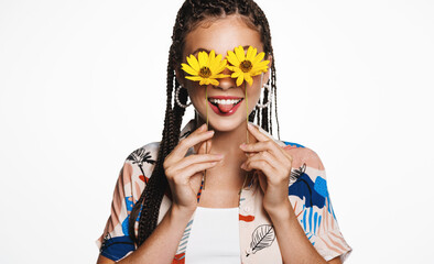 Summer vacation and holidays concept. Happy young woman holds two flowers against her eyes, floral glasses, smiles at camera, stands over white background