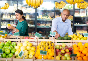 Married couple choosing fruits in grocery store