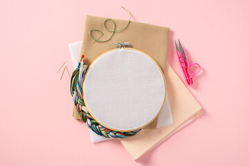 Embroidery hoop mockup on pink background with cross stitch items. Flat lay, top view.