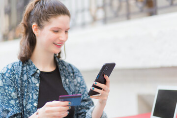Young woman using cell phone and credit card, online shopping concept