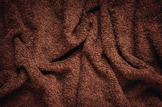 Furry wrinkled blanket texture. Close-up of brown material, may be used as background.