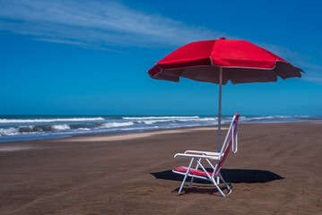 Empty beach chair and an umbrella on the seashore.