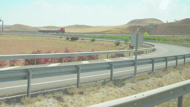 4K footage from moving vehicle on motorway parallel to opposite lane in remote rural areas against countryside landscape background.