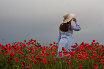 mujer con sombrero en campo de amapolas