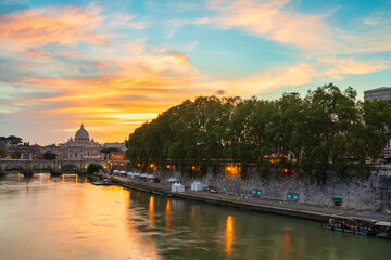 Naklejka premium St. Peter's basilica across Tiber River canal at sunset in Rome, Italy