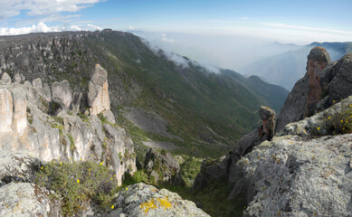 View from the rocks into the valley between the mountains with the misty sky on the horizon in the...