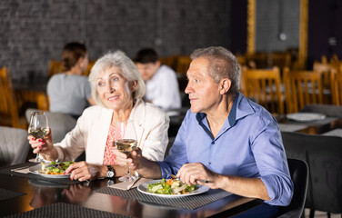 Fototapeta Couple of elderly man and woman having dinner and drinking wine together in restaurant obraz