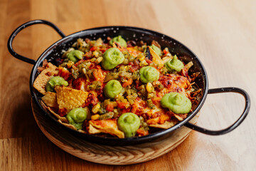 Plato de nachos con carne, queso y guacamole