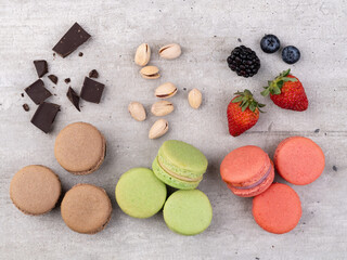 Dark chocolate, pistachio and berry macarons over wooden table