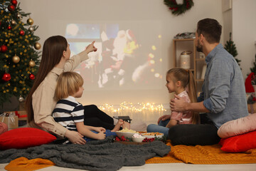 Family watching Christmas movie via video projector in cosy room. Winter holidays atmosphere
