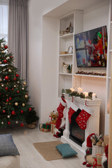 TV set with Christmas movie above fireplace in cosy room. Winter holidays atmosphere