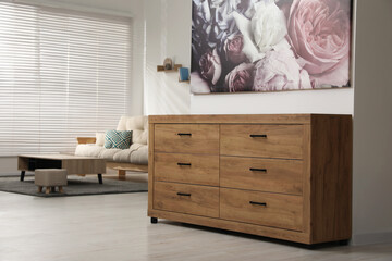 Wooden chest of drawers near white wall in stylish room