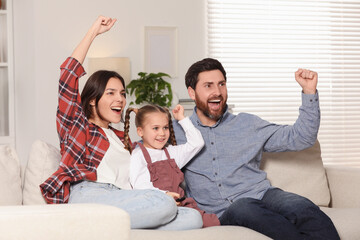 Excited family watching TV on sofa at home