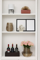 Shelves with different decor and rose flowers indoors. Interior design