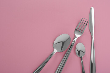 Stylish cutlery set on pink background, flat lay. Space for text