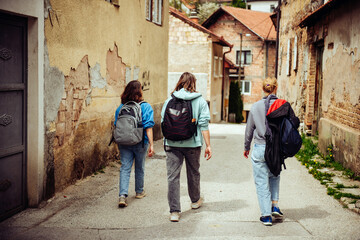 Obraz na płótnie Canvas Three female friends of the traveler are walking through the narrow streets of the old European city. Hiking in historical places of the world