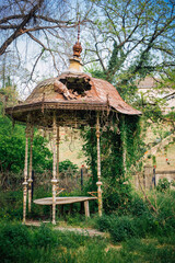 An old dilapidated vintage gazebo in the thickets of an abandoned territory