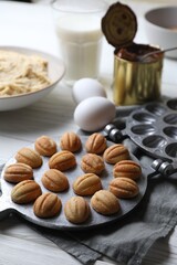 Fototapeta na wymiar Delicious walnut shaped cookies with condensed milk and ingredients on white wooden table, closeup