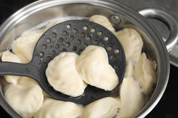 Boiling delicious dumplings (varenyky) on skimmer over pot, closeup