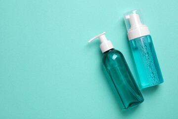 Different cleansers on turquoise background, flat lay and space for text. Cosmetic product
