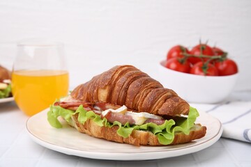 Tasty croissant with brie cheese, ham and bacon on white table, closeup