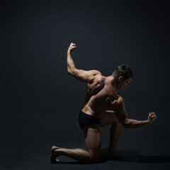 Muscular athlete in an epic pose, dark background, bright contrast light