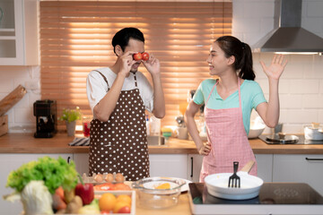 Happy Asian couple preparing delicious dinner in the kitchen at home.