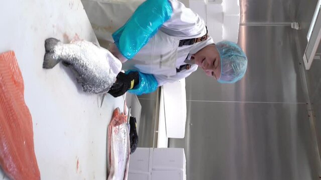Working Team In A Seafood Processing Factory. Man sprinkles the spices on the salmon fillet.