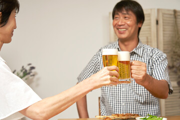 自宅でビールで乾杯をする熟年夫婦