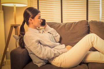 this portrait captures a beautiful young asian woman, engaging in a phone call while leisurely...