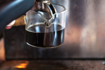 Close up of a glass cup with shot of espresso on a coffee machine