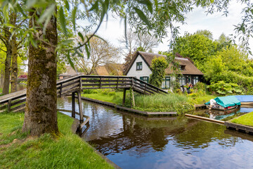 Fototapeta na wymiar Traditional thatched roof home in famous Giethoorn village in the Netherlands. Where no roads and only canals for transportation.