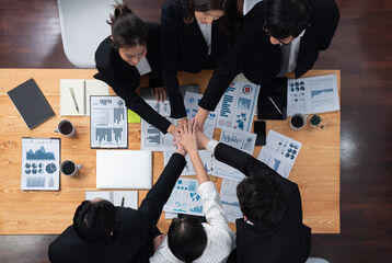 Top view cohesive group of business people join hands together, form circle over table filled with...