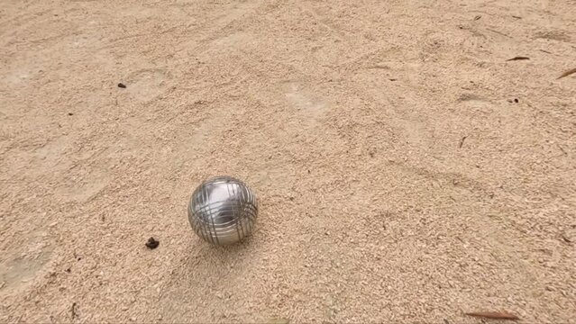 Metal Ball On Sandy Court Of Petanque Game - tracking shot