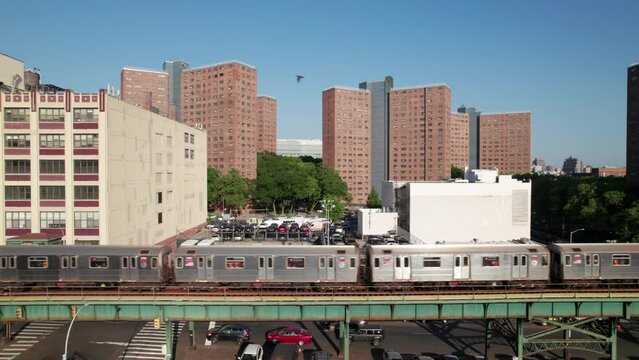 Side shot of passing subway trains in New York City, housing projects in background.