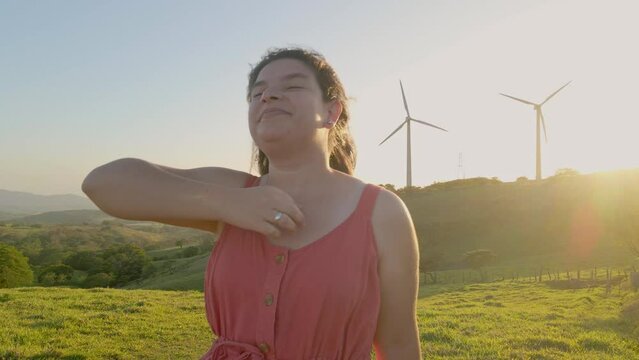 Video image of a beautiful woman full of fullness opening her arms to enjoy the wind with a beautiful sunset in the background. 