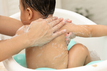 Close up hand of mother bathing on back of her son in warm water. Happy adorable newborn infant relax and comfortable good moment with mom. Newborn baby care concept