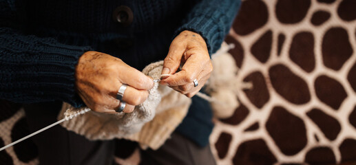 Obraz premium Mujer latina, adulto mayor , feliz y concentrada, en la sala de casa usando unos palitos de tejer y lana de oveja, concepto de vida cotidiana tradicional, tejedora tradicional, enfoque selectivo.