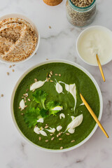 Healthy breakfasts, green broccoli and spinach cream soup with sunflower seeds and yogurt, buckwheat bread, top view