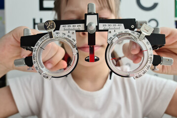 Child holding trial frame for medical optician concept in clinic.