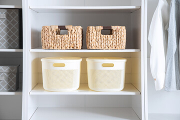 This image depicts a white closet with multiple baskets on the shelves and several articles of...