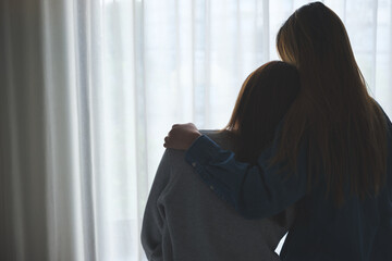 Silhouette image of a woman hugging her friend to comforting and giving encouragement in bedroom
